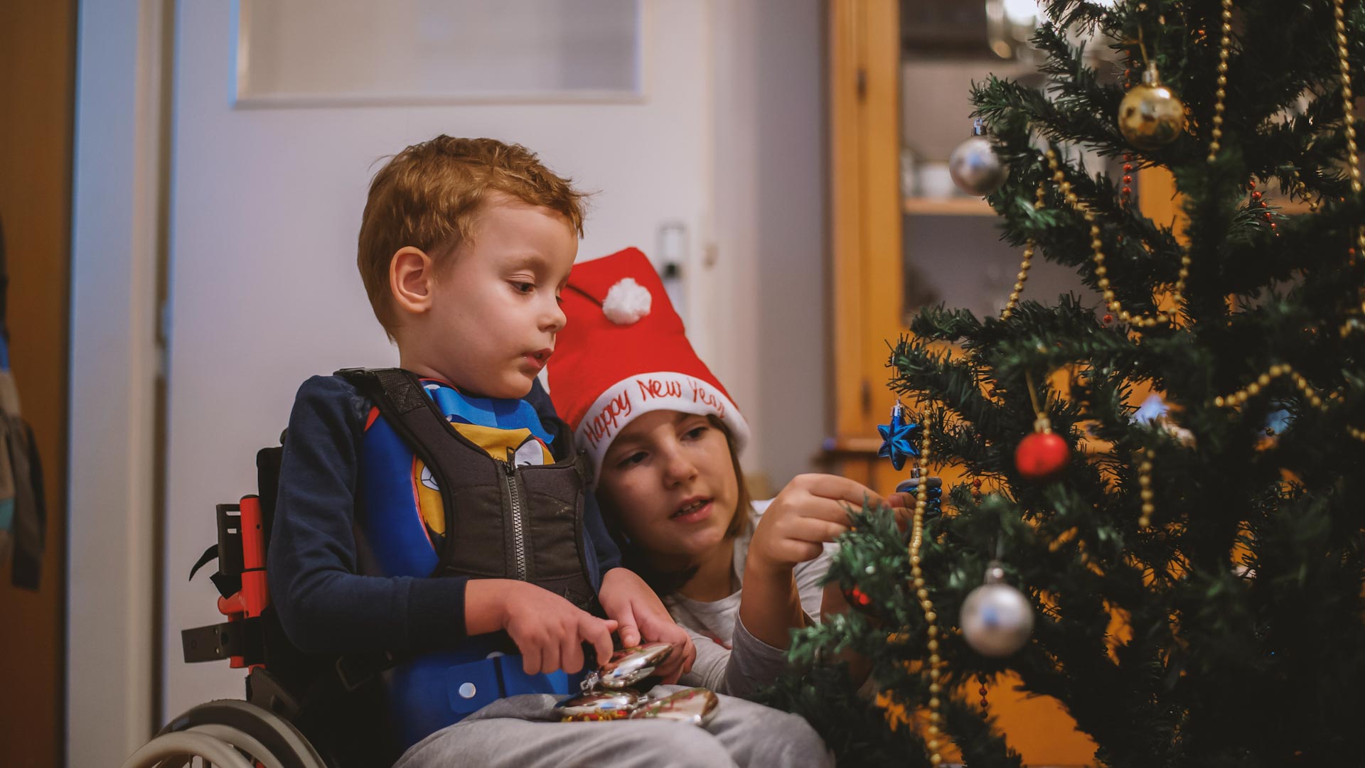 Disabled boy and sister decorating the Christmas tree