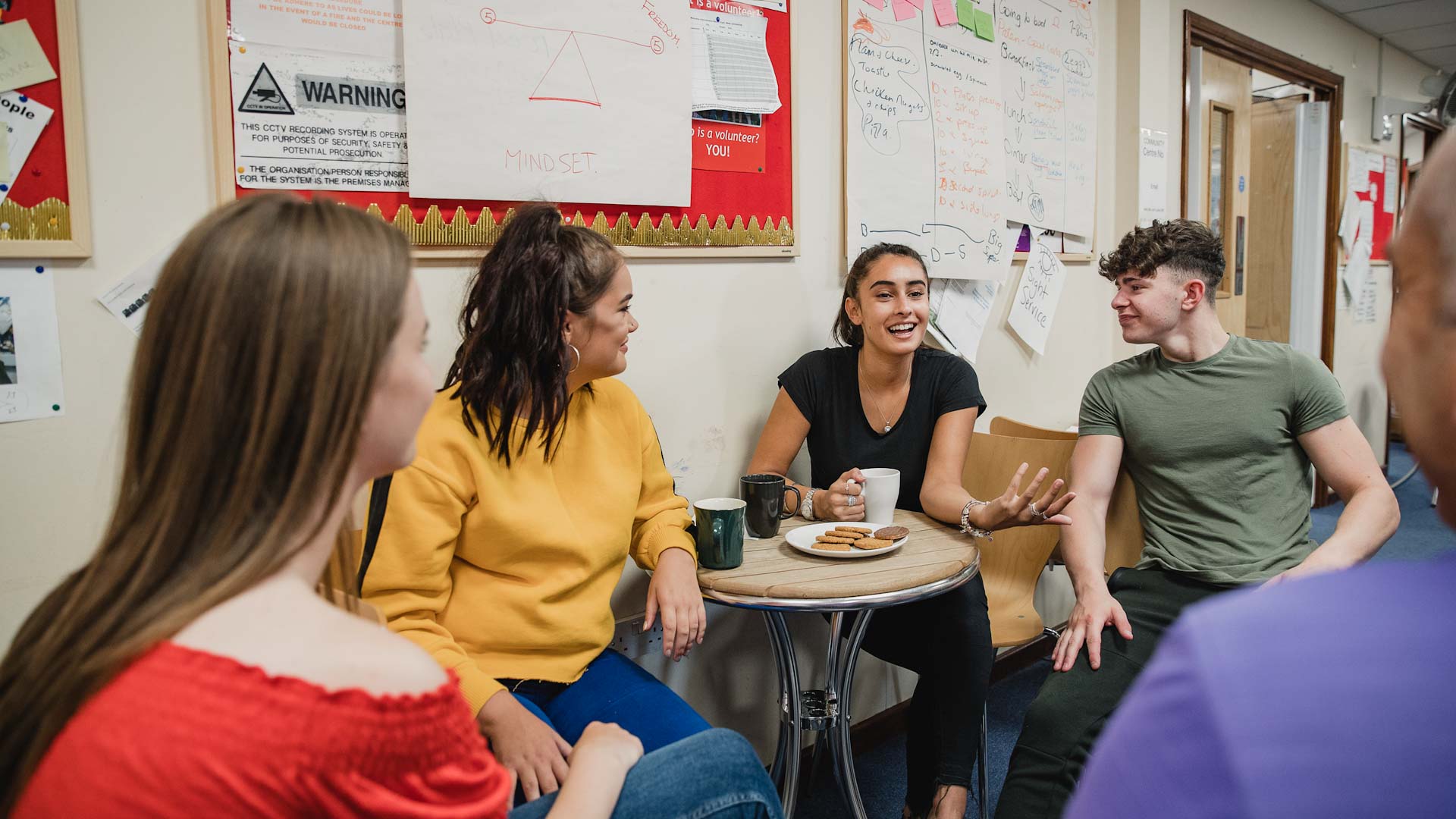 Group of young people sat around chatting and laughing