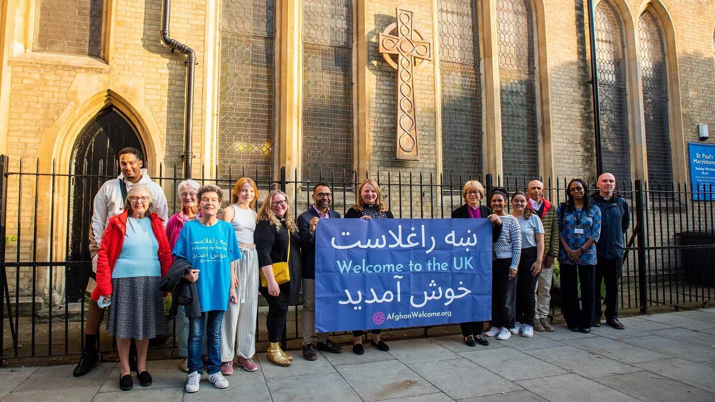 Congregation with Afghan welcome banner outside St Paul's Church