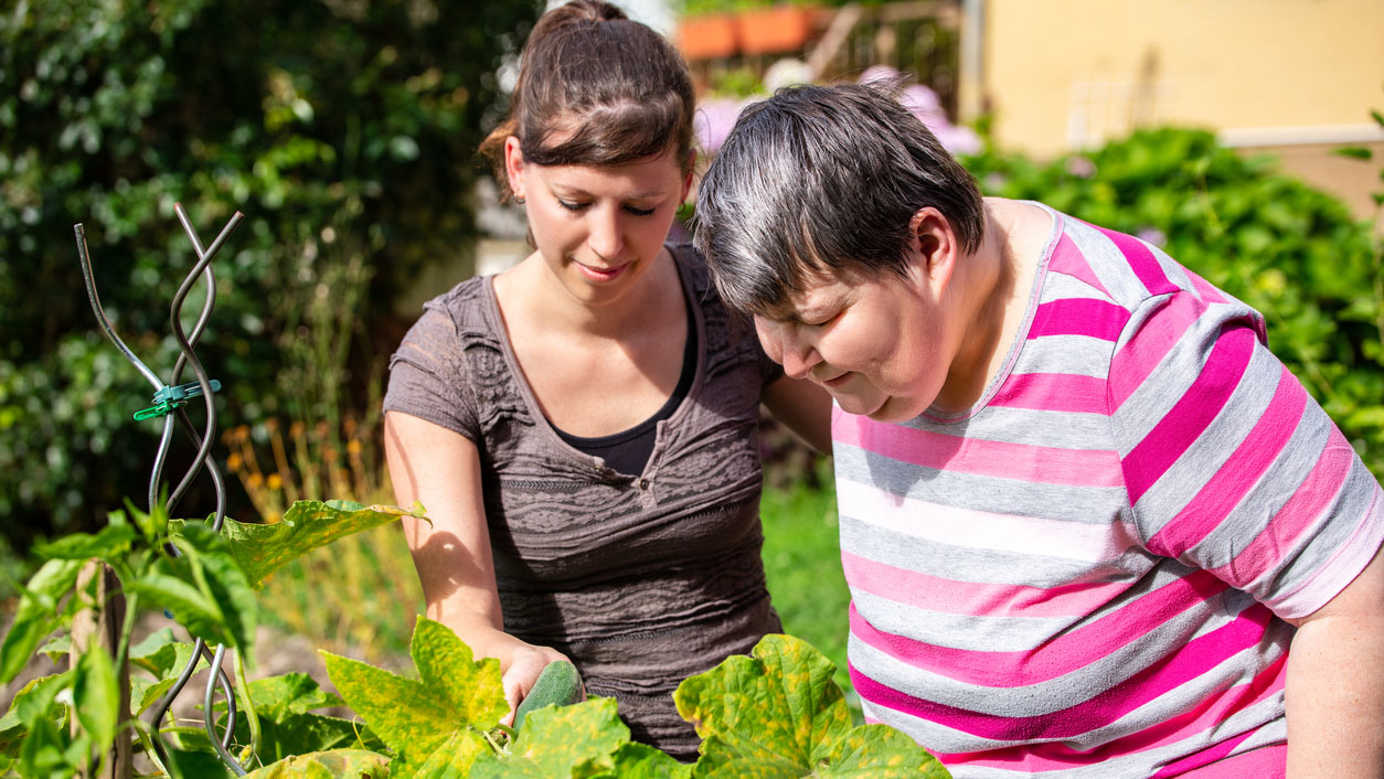Carer and disabled woman looking at a plant